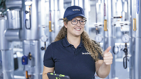Female Leadec in a technical room employee hold thumbs up.